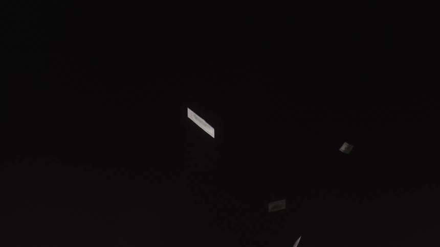 Dollar bills flutter through the air against a dark background