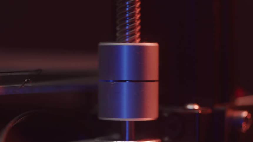 A shiny metal machine part glows under warm industrial lighting