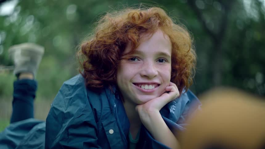 The girl is laying down and smiling outside