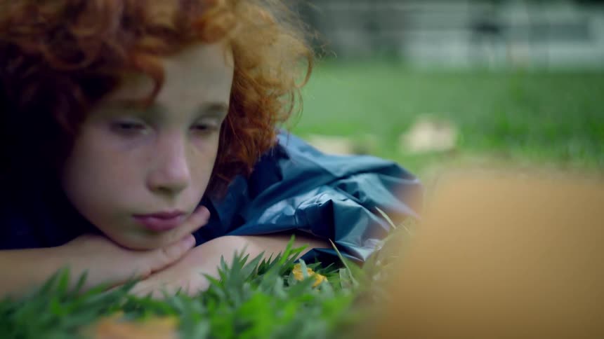 The boy is laying in the grass