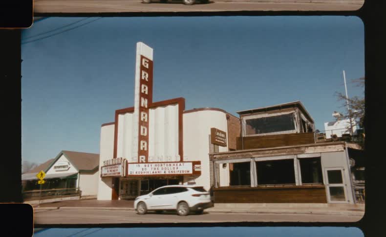 Cars drive past the iconic vintage granada theater on a bright sunny day