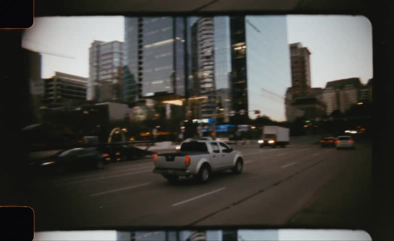A pick up truck drives down a busy street in an urban city at sunset