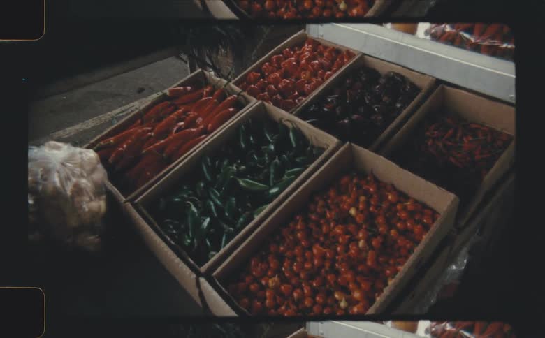 Various colorful peppers are displayed in cardboard boxes at a market
