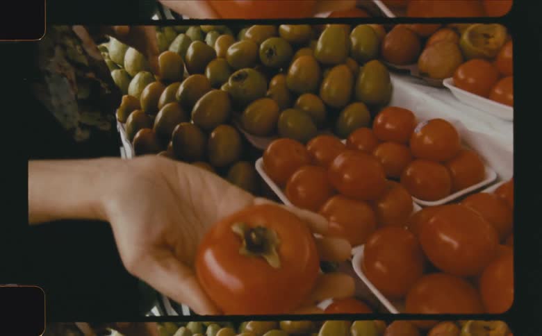 A woman picks a tomato at the market