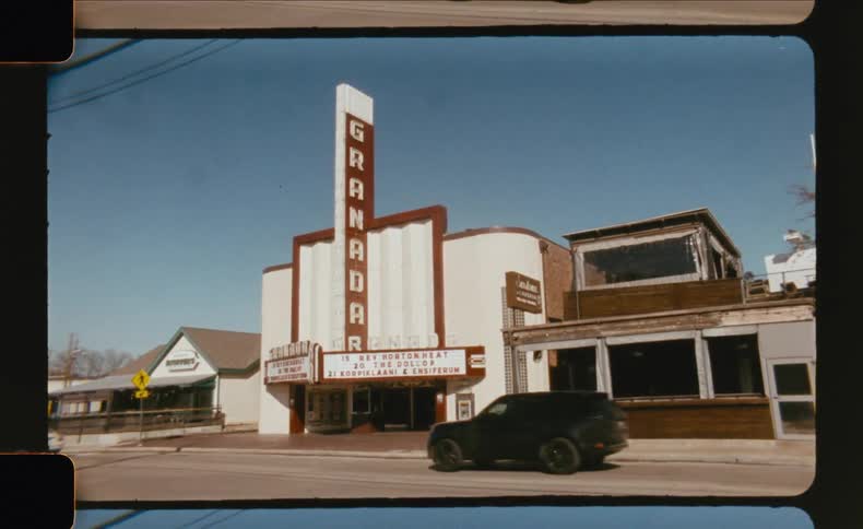 Cars drive past the iconic granada theater on a bright sunny day