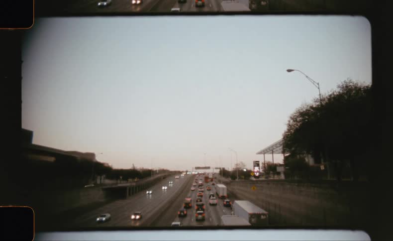 Traffic flows along a multi lane highway at dusk as seen from an overpass