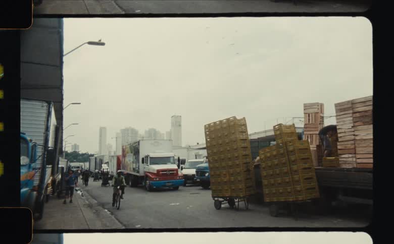 A scene of a street with a packing truck unloading as a bike goes past its shot on film