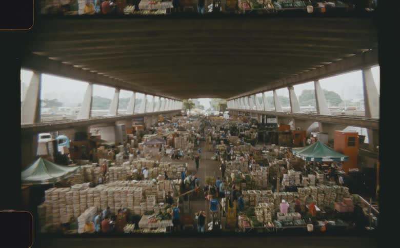 A wide interior shot of a bustling marketplace under a large covered structure