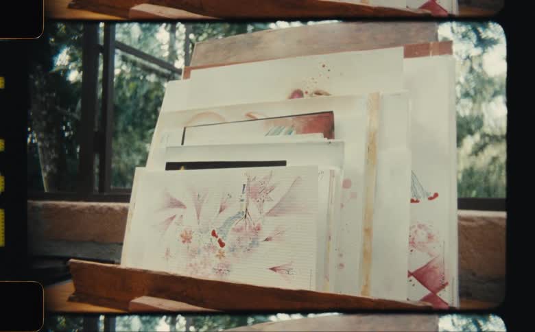 Multiple pieces of art occupy a wooden frame near the window