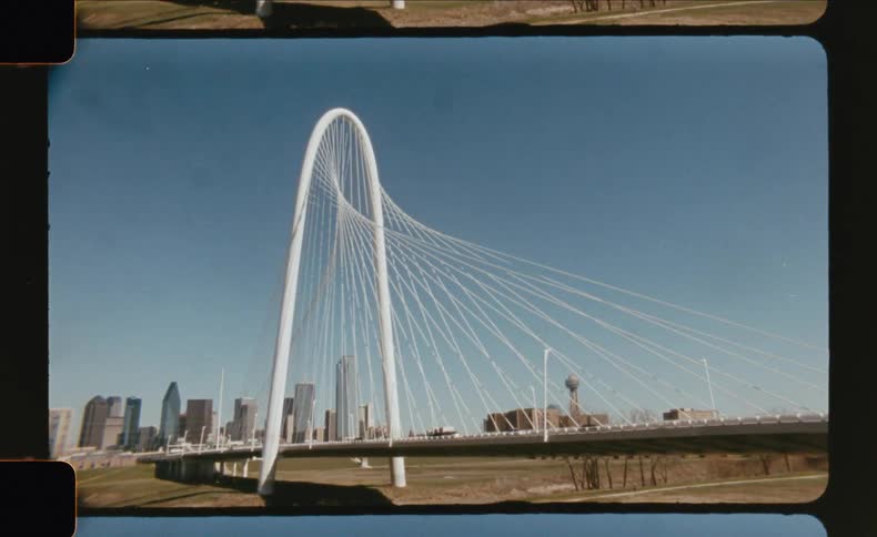Modern suspension bridge in front of a city skyline on a clear day