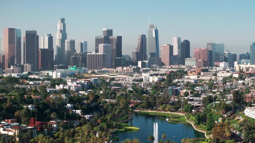 A wide shot of a large city skyline with a park and lake in the foreground