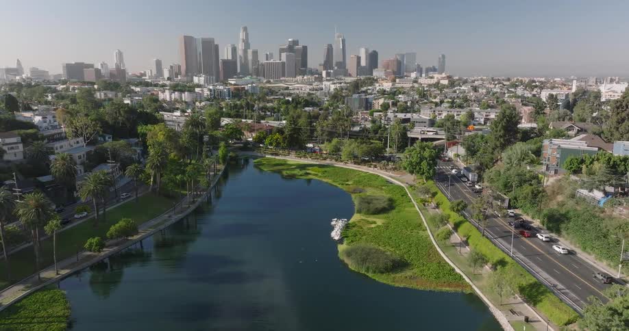 A lake winds through a city park with skyscrapers in the distance