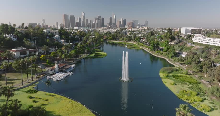 Aerial view of a city park lake with fountains and downtown skyscrapers in the background