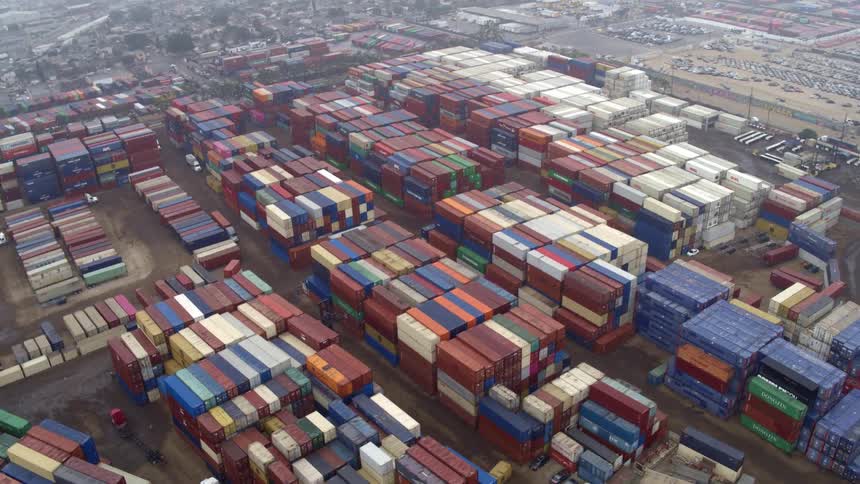Stacks of colorful shipping containers fill a busy port yard