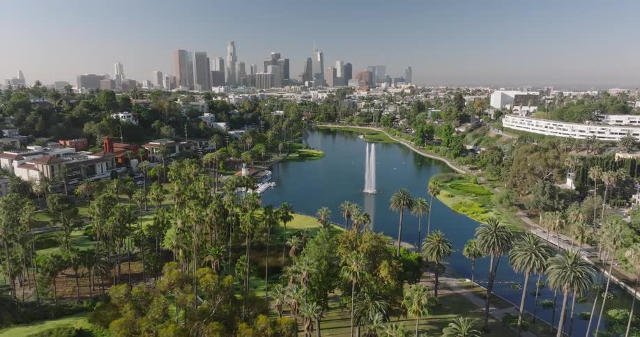 Echo Park Lake  and fountain is seen from above with skyscrapers of downtown Los Angeles in the background