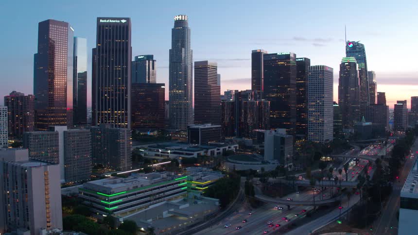 A wide cityscape view of downtown Los angeles at sunset with skyscrapers and traffic below
