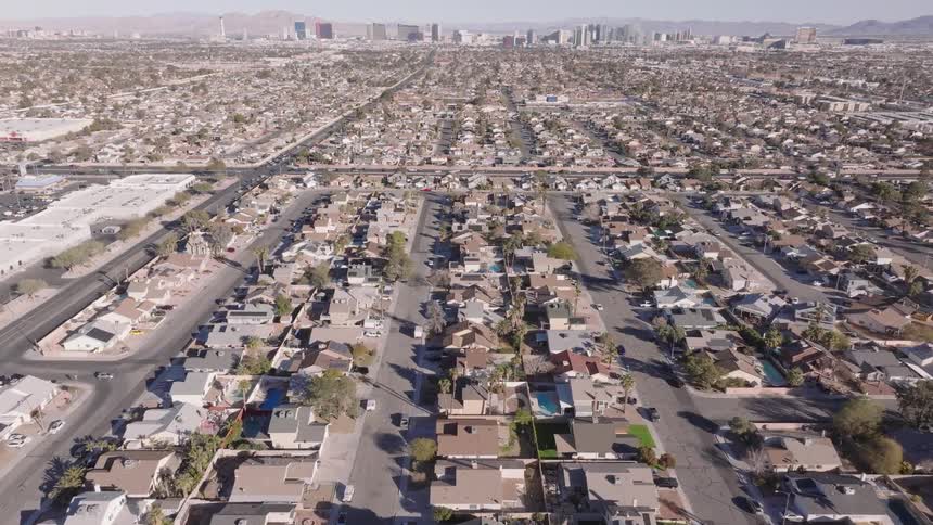 An aerial shot captures a vast suburban landscape during the day characterized by a dense arrangement of residential houses and green spaces the orderly layout of streets and rooftops under natural light provides a clear view of the sprawling community