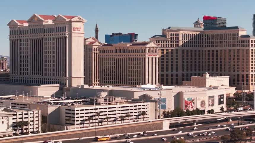A wide daytime shot of las vegas boulevard showing iconic hotels and heavy road traffic