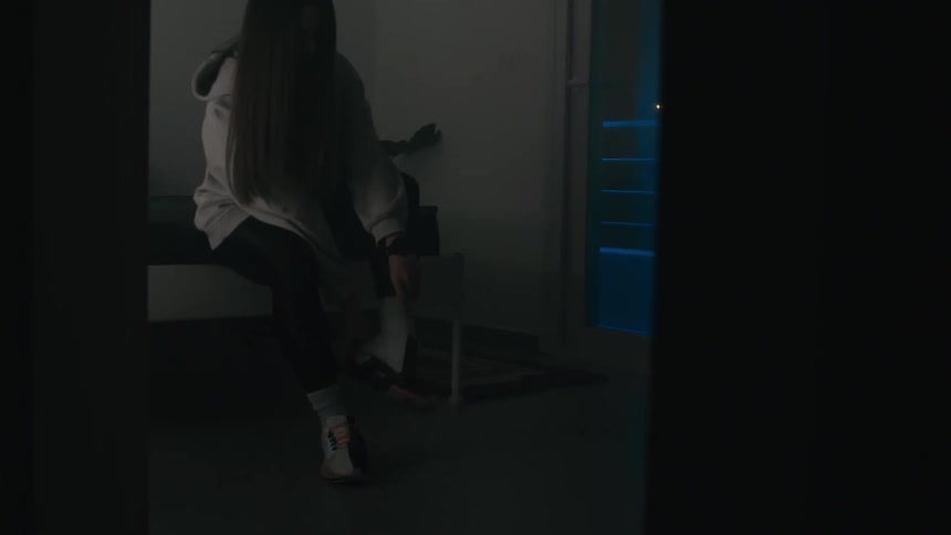 A woman puts on her shoes and walks out of the room