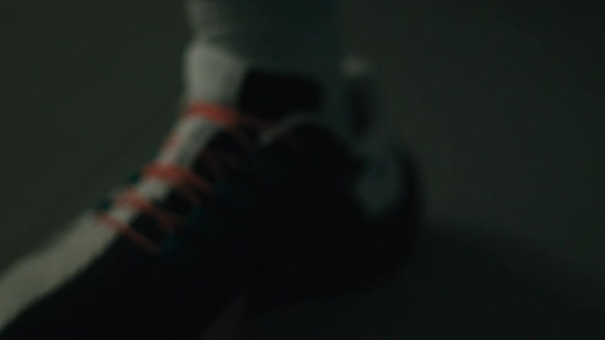 A person wearing sneakers and socks ties the laces before standing up