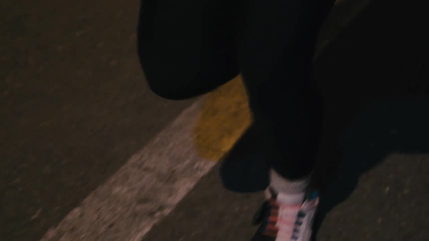 A woman with a pony tail runs along a road at night