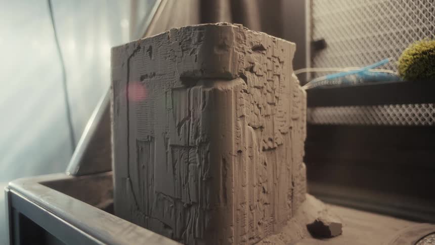 A 3d printer piece extrudes claylike material in precise layers to form a vertically ridged object