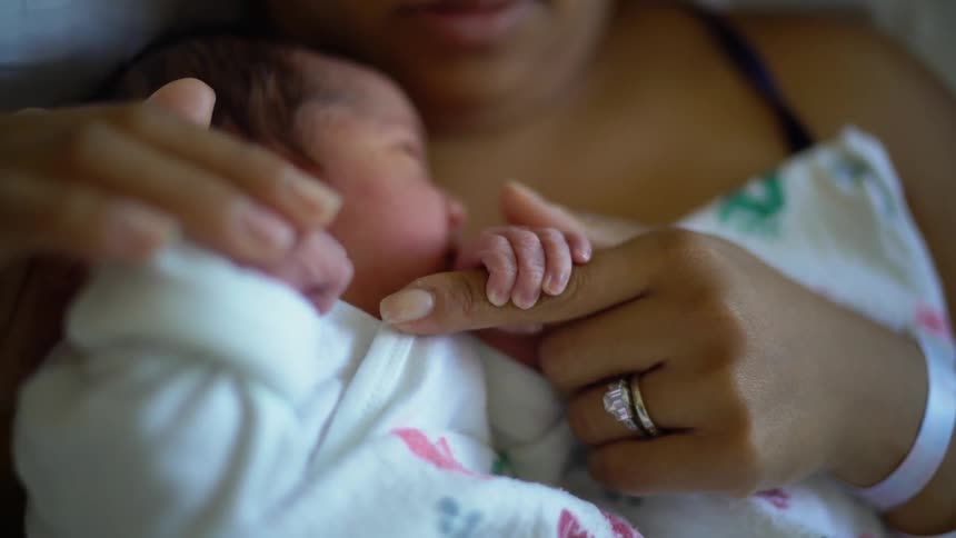 A woman cradles a baby in her arms