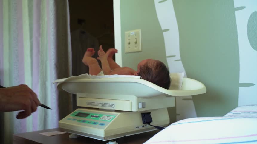 A doctor weighs an infant