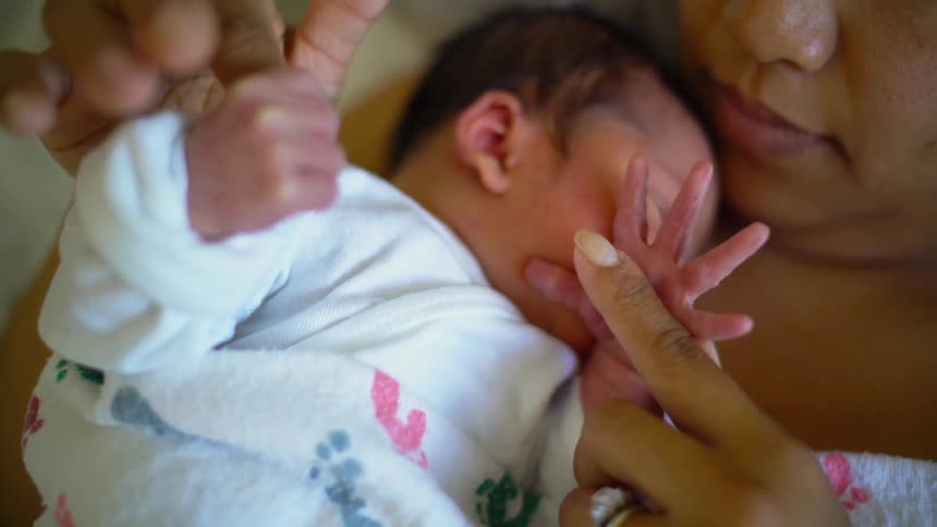 A close up of a lady holding a baby on her chest