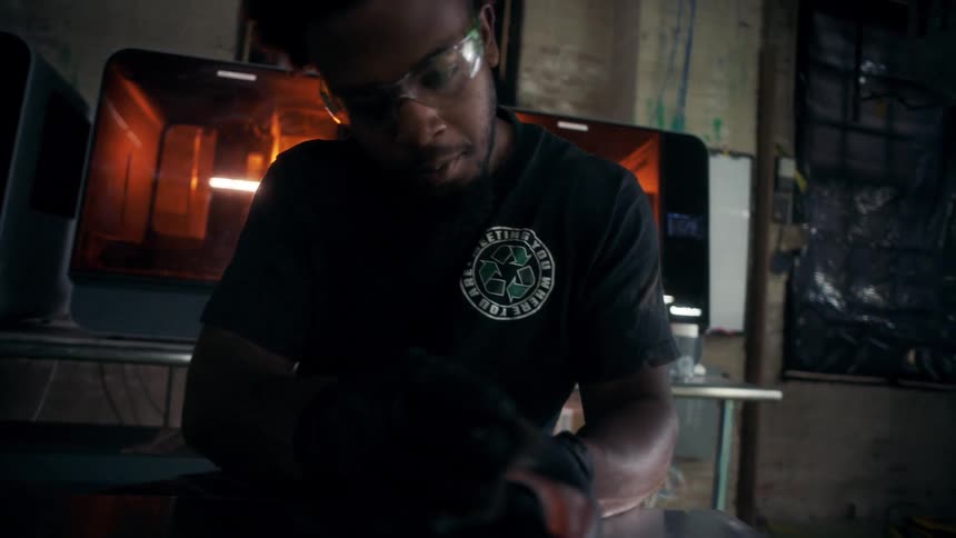 The worker is sanding a piece of metal in the factory