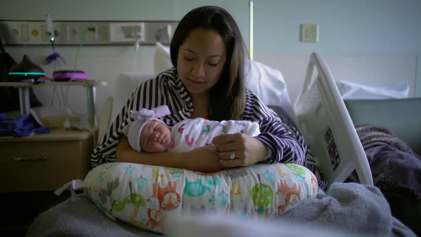 A new mother holders her infant in a hospital bed
