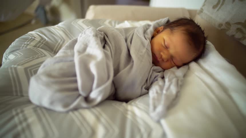 Newborn baby moving around in blanket as it sleeps