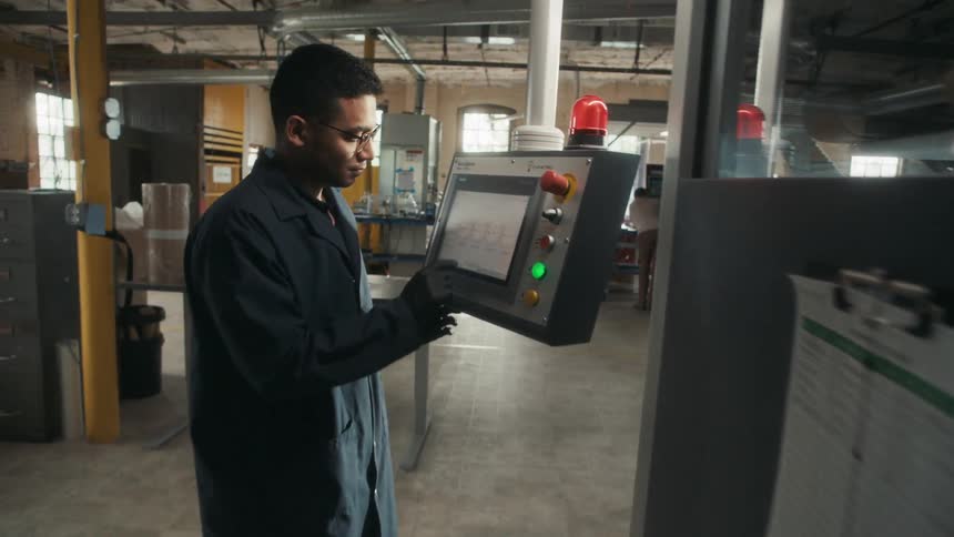 Man operating control panel in bright industrial setting
