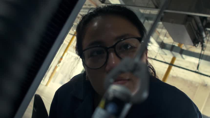 The woman is looking close at material in the machine