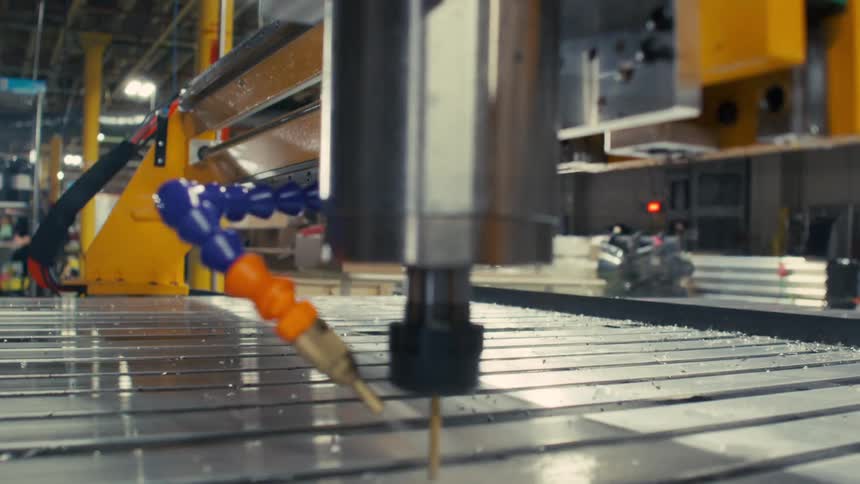 Close up of an automatic drilling machine drilling holes into metal bars in a factory