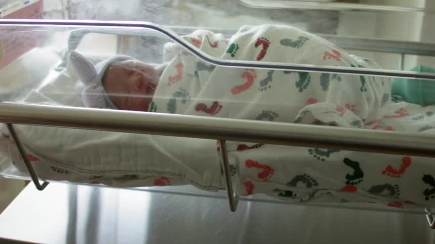 A swaddled baby in a hospital crib