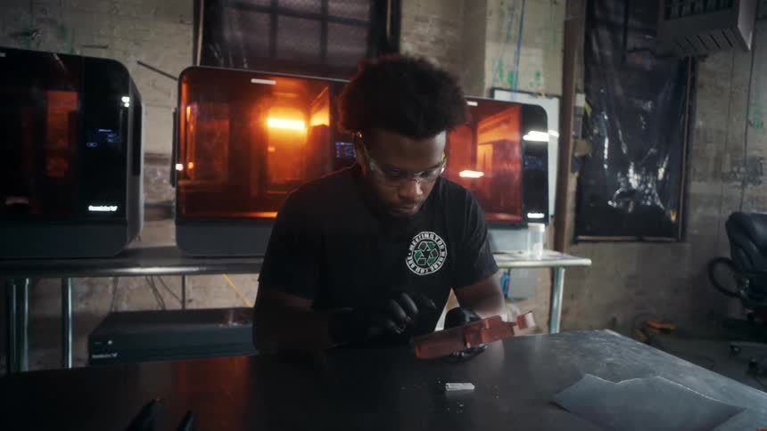 The worker is using a pen knife to carve into an object