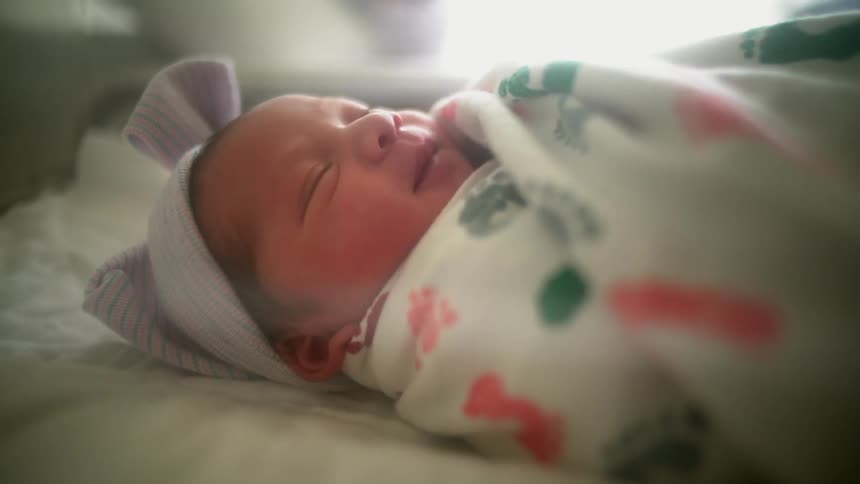 An infant rests swaddled in a blanket