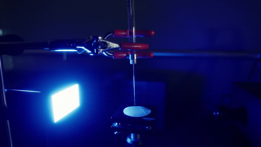 Robotic hand manipulates a tool in a workshop near a glowing surface