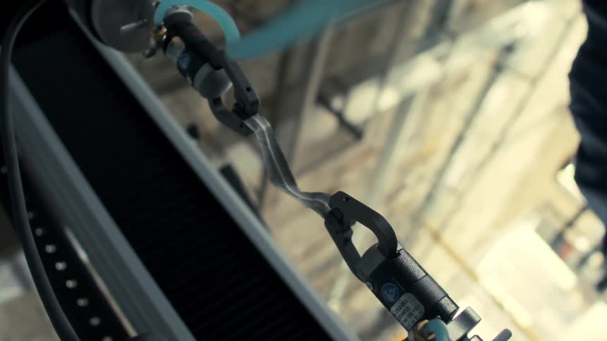 A robotic arm stretches a bundled cable in a dimly lit industrial setting