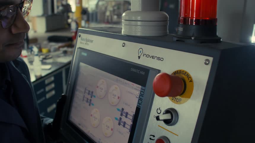 Close up of male worker moving an electrospinning machine in lab factory during daytime