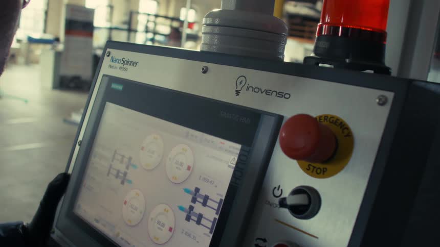 A worker moves the control panel of an industrial machine around an industrial complex