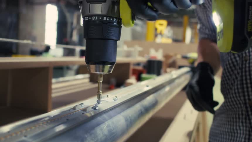 Worker uses a battery powered drill while working in a factory
