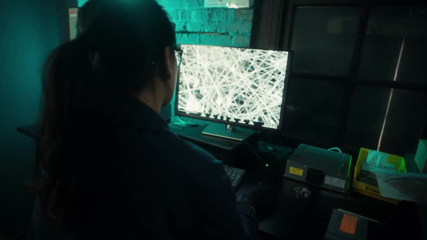 A woman works at a computer in a dimly lit tech workspace