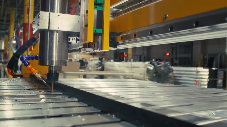 Close up of an automatic drilling machinery drilling holes into metal bars in a factory