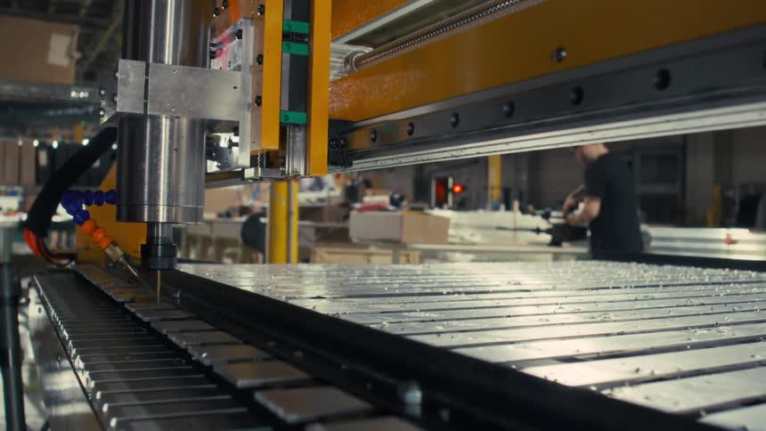 Close up of an automatic drilling machinery drilling holes into metal bars in a factory during daytime