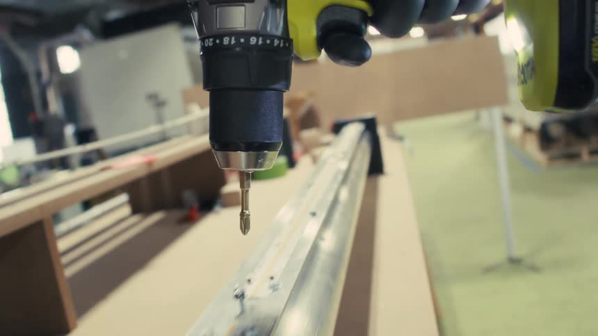 A person in the factory uses a power drill
