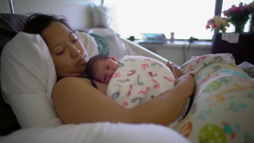 A woman holds her newborn baby on her chest