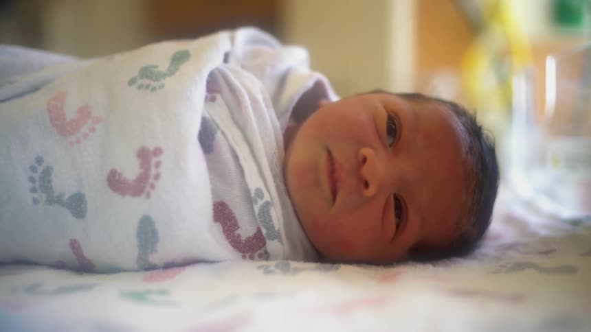 A baby is tightly wrapped in a blanket