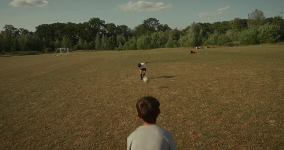 Two boy children are playing soccer together in a field